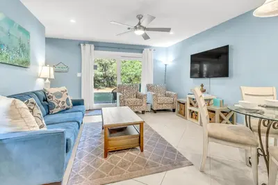 a living room with a blue couch and a table at Somewhere in the Sun in Santa Rosa Beach