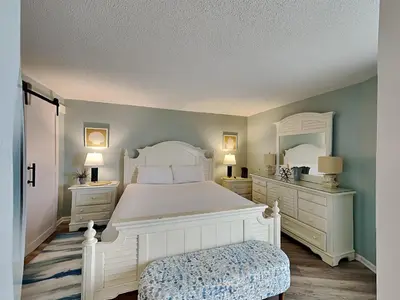 a bedroom with a large white bed and a mirror at Edgewater Tower III #705 in Panama City Beach