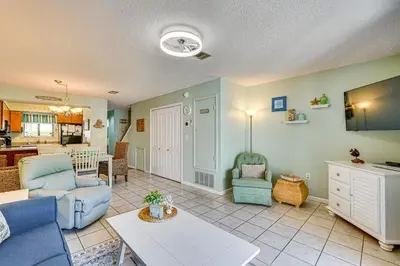 a living room with blue chairs and a table at Walk to Shore PCB Home with Balcony and Pool Access! in Panama City Beach