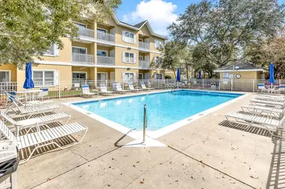 a swimming pool with lounge chairs and a building at Coastside in Santa Rosa Beach