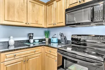 a kitchen with wooden cabinets and stainless steel appliances at Coastside in Santa Rosa Beach