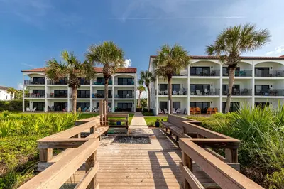 a boardwalk leading to a hotel with palm trees at Paradise Palms in Santa Rosa Beach