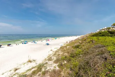 a beach with people and umbrellas and the ocean at Paradise Palms in Santa Rosa Beach