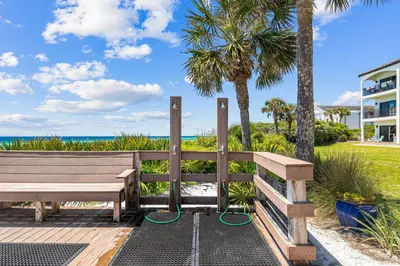 a wooden bench next to the beach with palm trees at Sea Palms in Santa Rosa Beach