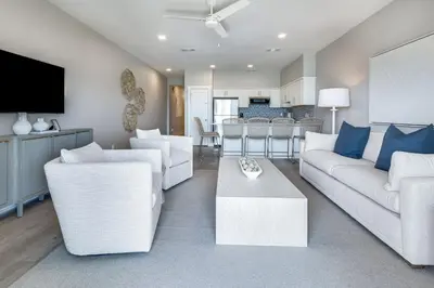 a living room with white couches and a kitchen at Sea Palms in Santa Rosa Beach