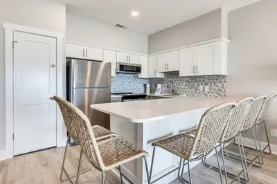 a kitchen with white cabinets and a counter with chairs at Sea Palms in Santa Rosa Beach