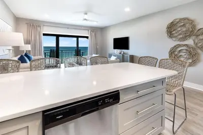 a kitchen with a white counter top and a living room at Sea Palms in Santa Rosa Beach
