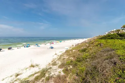 a beach with people and umbrellas and the ocean at Palms of Seagrove D5 in Santa Rosa Beach