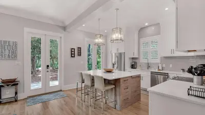 a white kitchen with a island with bar stools at Magnolia Breeze in Santa Rosa Beach