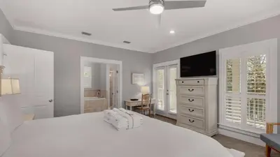 a white bedroom with a white bed and a television at Magnolia Breeze in Santa Rosa Beach