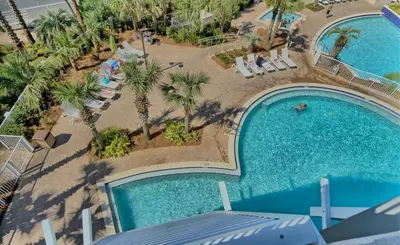 an overhead view of a pool with chairs and palm trees at Resort-Style Lake-View Condo, 5 Pools, Hot Tubs, Walk to Beach in Panama City Beach
