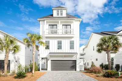 a white house with palm trees in front of it at Salty Sons in Inlet Beach