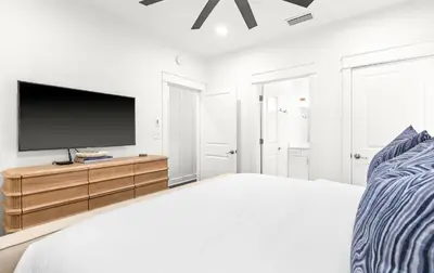 a white bedroom with a bed and a flat screen tv at The Palms in Santa Rosa Beach