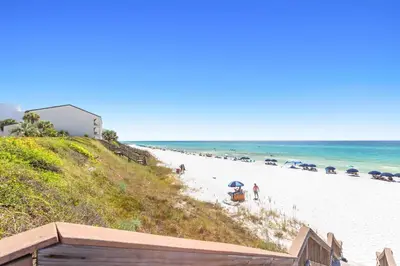 a beach with people and umbrellas on it at The Palms in Santa Rosa Beach
