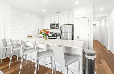 a white kitchen with a large white counter and stools at The Palms in Santa Rosa Beach