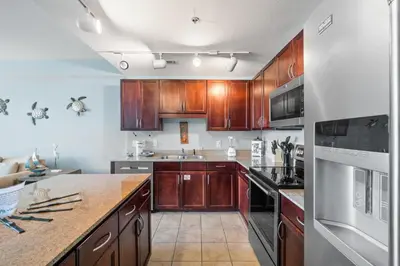 a kitchen with wooden cabinets and a counter top at Lake-View Condo Near Beach,5 Pools, 2 Hot Tubs, Balcony & Resort Amenities in Panama City Beach