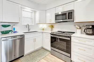 a kitchen with white cabinets and a stove top oven at Seagroovy in Seagrove Beach
