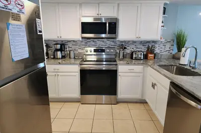 a kitchen with a stainless steel stove and a microwave at Oceanfront Condo - Balcony Views & Beach Access in Panama City Beach