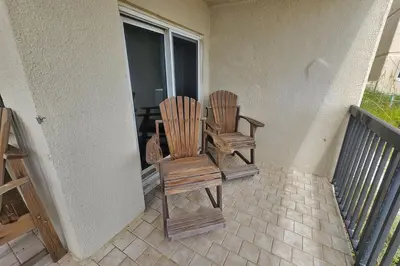 two wooden chairs sitting on the porch of a house at Oceanfront Condo - Balcony Views & Beach Access in Panama City Beach