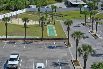 an aerial view of a parking lot with palm trees at Oceanfront Condo - Balcony Views & Beach Access in Panama City Beach