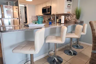 a kitchen with a counter with four bar stools at Oceanfront Condo - Balcony Views & Beach Access in Panama City Beach