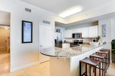 a kitchen with a large island with bar stools at Tidewater 3006 by Emerald Cost Retreats in Panama City Beach