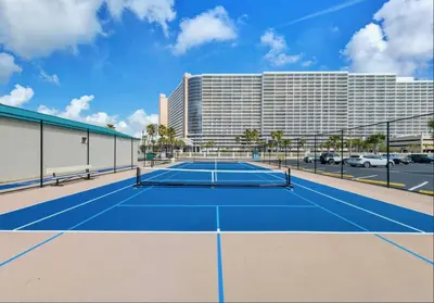 a tennis court in front of a hotel at Sunbird low Floor 2BR! Free Beach Chair Service! by Dolce Vita Getaways PCB in Panama City Beach
