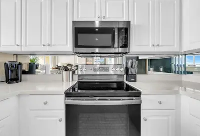a kitchen with white cabinets and a stove and a microwave at BeachFront- 5 Pools, Starbucks, Movies - Majestic Beach Resort in Panama City Beach