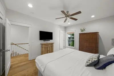 a white bedroom with a bed and a flat screen tv at Sweet Sea-esta on 30A in Inlet Beach