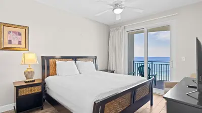 a bedroom with a bed and a balcony with the ocean at 2 Beachfront Condos BBQ Balconies Resort Pool Hot Tub Direct Beach Access in Panama City Beach