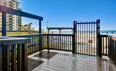 a wooden deck with a gate and the beach at Renovated Penthouse! Free Beach Chairs Included! by Dolce Vita Getaways PCB in Panama City Beach