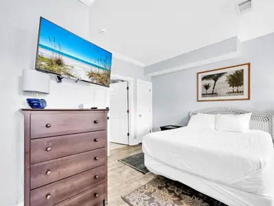 a bedroom with a bed and a dresser with a tv at 3B - The Seaglass Shack in Panama City Beach