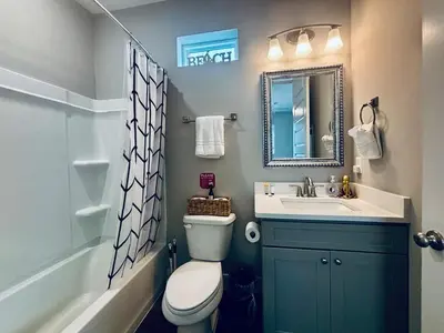 a bathroom with a toilet and a sink and a mirror at The Salty Blue in Panama City Beach