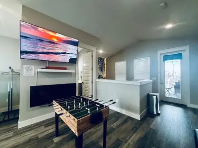 a room with a foosball table and a large screen at The Salty Blue in Panama City Beach