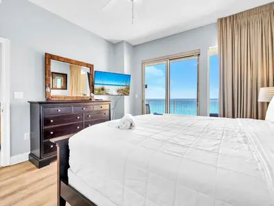 a bedroom with a large white bed and a mirror at Treasure Island 511 in Panama City Beach
