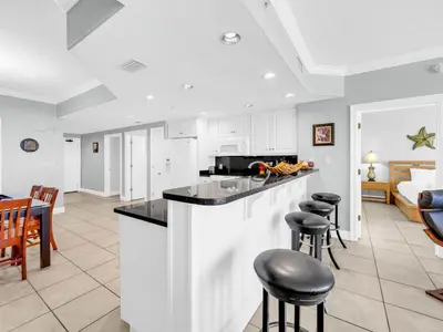 a kitchen with white cabinets and black counter tops at Treasure Island 1102 in Panama City Beach
