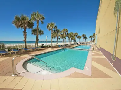 a swimming pool with palm trees and the beach at Sterling Reef 501 by Emerald Coast Reteats in Panama City Beach