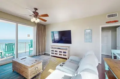 a living room with a couch and a flat screen tv at Sterling Reef 501 by Emerald Coast Reteats in Panama City Beach
