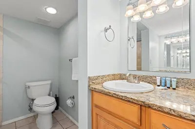a bathroom with a sink and a toilet and a mirror at Commodore 0201 in Panama City Beach