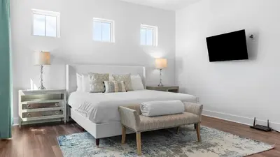 a white bedroom with a bed and a chair at Family-Friendly 30A Stay Pool Access Firepit Steps to the Beach Driftwood Dreams by AvantStay in Inlet Beach