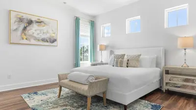 a white bedroom with a bed and a chair at Family-Friendly 30A Stay Pool Access Firepit Steps to the Beach Driftwood Dreams by AvantStay in Inlet Beach