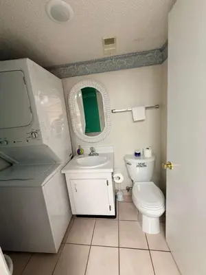 a bathroom with a toilet and a sink and a mirror at Sand, Sea & Air at Pinnacle Port A-301 in Panama City Beach