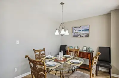 a dining room with a glass table and chairs at Aquavista 603W by Emerald Coast Retreats in Panama City Beach