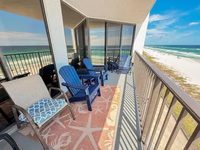 a balcony with chairs and tables and the beach at Aquavista 603W by Emerald Coast Retreats in Panama City Beach