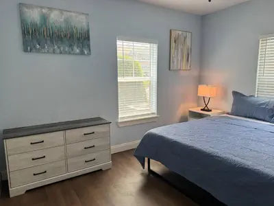 a bedroom with a bed and a dresser and two windows at Beautiful Resort Condo Panama City Beach King Bed in Panama City Beach