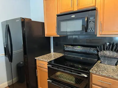 a kitchen with a microwave and a black refrigerator at Beautiful Resort Condo Panama City Beach King Bed in Panama City Beach