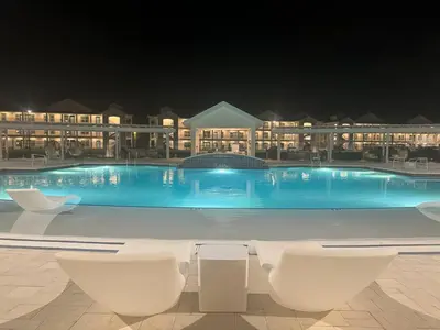 a large swimming pool at night with white chairs at Beautiful Resort Condo Panama City Beach King Bed in Panama City Beach