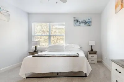 a white bedroom with a bed and a window at King Condo Panama City Beach All Amenities Resort in Panama City Beach