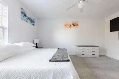 a white bedroom with a bed and a night stand at King Condo Panama City Beach All Amenities Resort in Panama City Beach