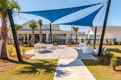 a patio with chairs and palm trees in front of a building at King Condo Panama City Beach All Amenities Resort in Panama City Beach